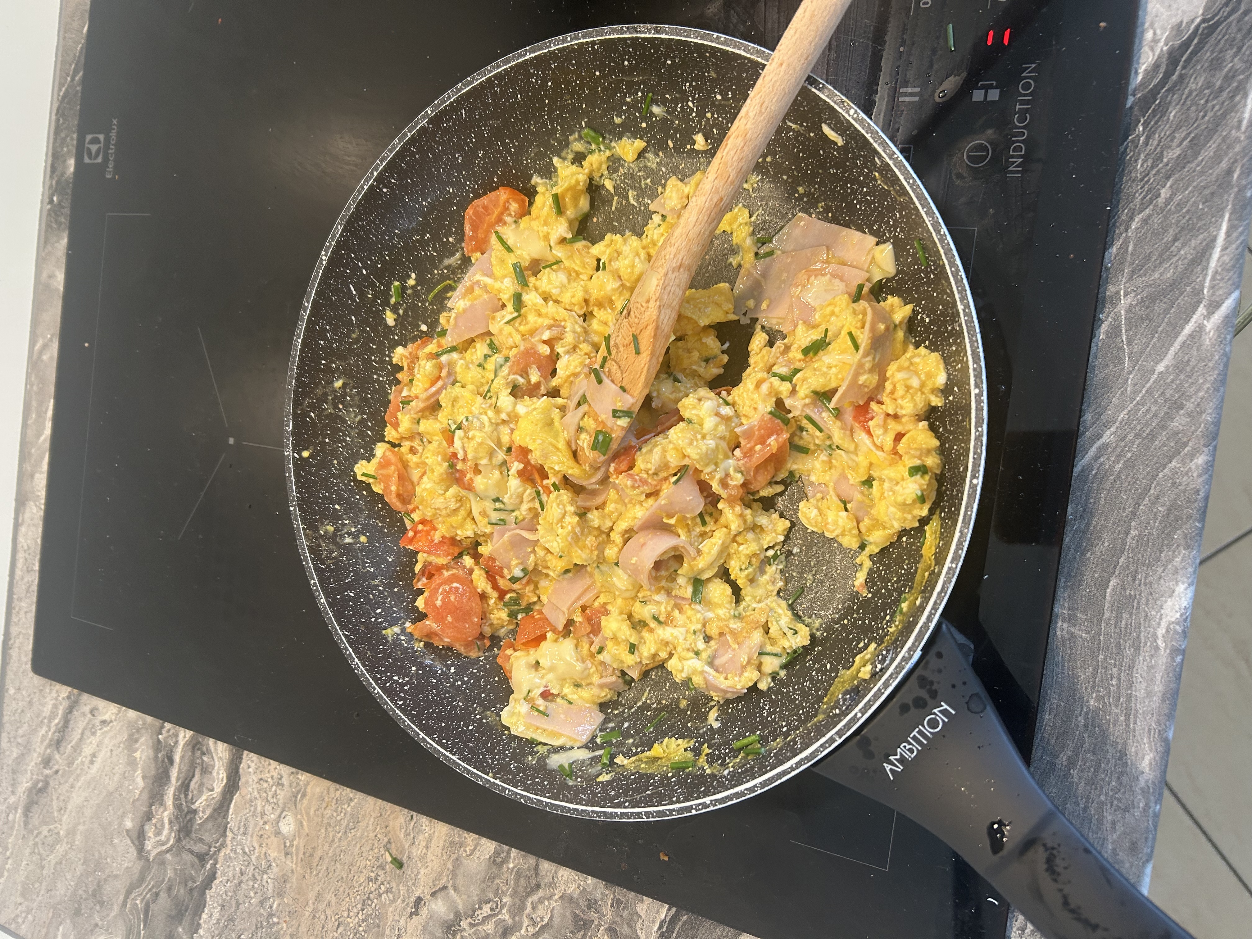 Scrambled eggs with cherry tomatoes, ham, gouda, and chives
